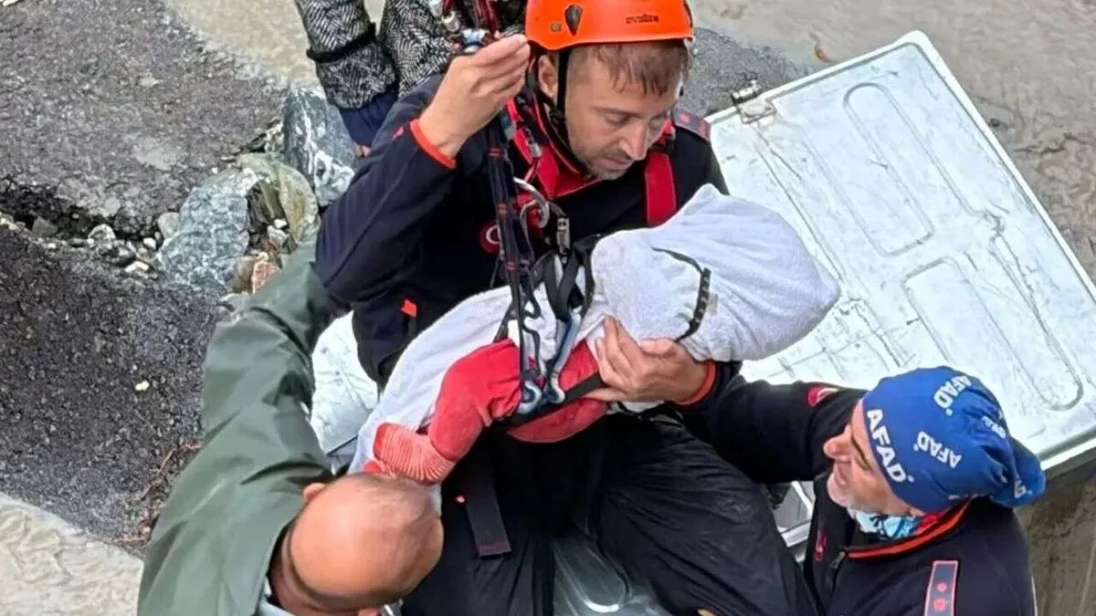 AFAD personelinin selde kurtardığı bebeği kucağında taşıması