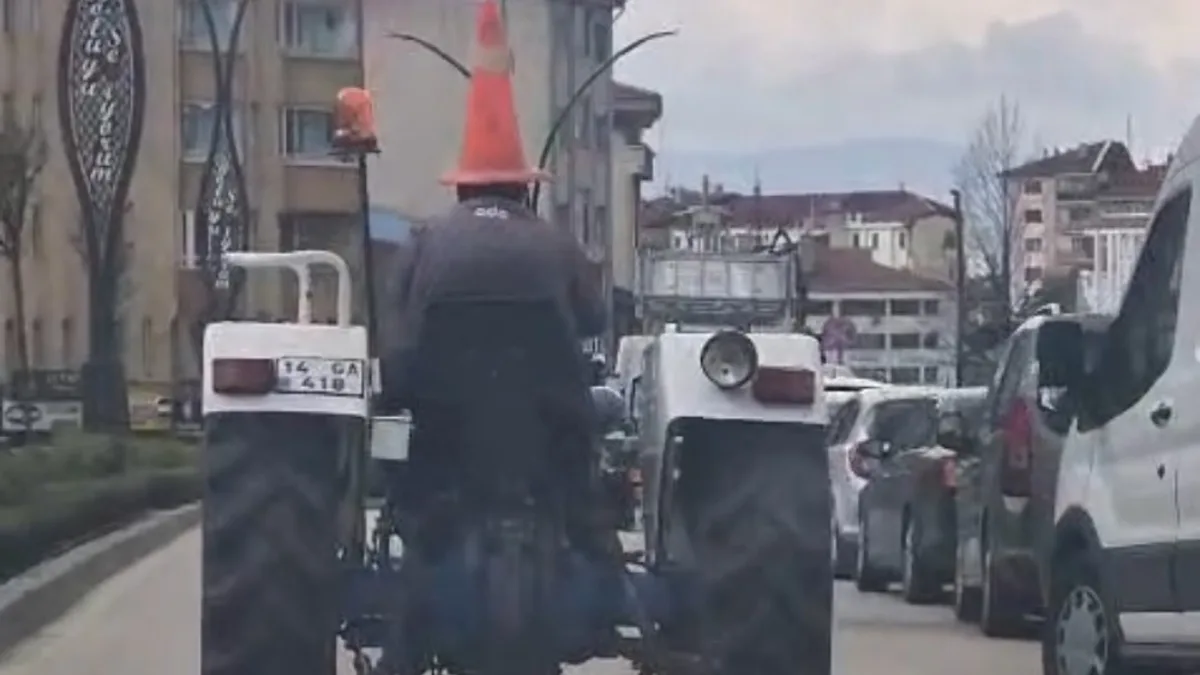Başına trafik dubası geçirmiş traktör sürücüsünün trafikte ilerlerken görüntülenmesi