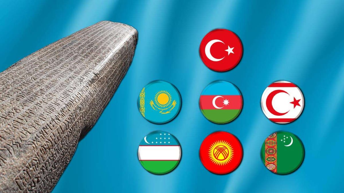 Üzerinde yazı işlemeleri bulunan taş anıt ve Türk dünyasındaki ülkelerin bayrakları